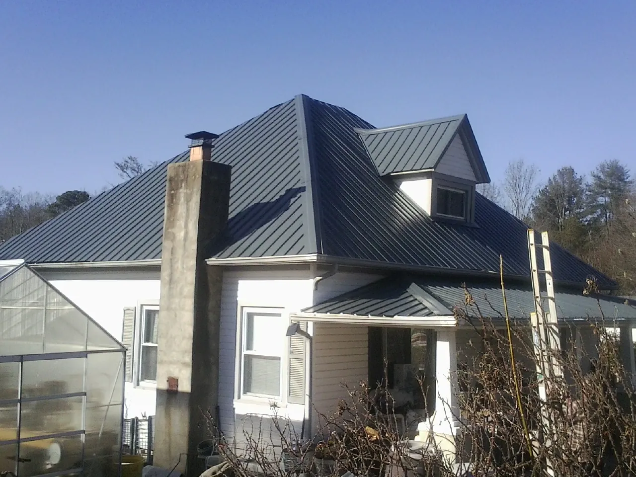 Dark blue standing seam metal roof on a white farmhouse with dormer — Slate & Tile Roof Repair by Roofing Brothers in Parowan