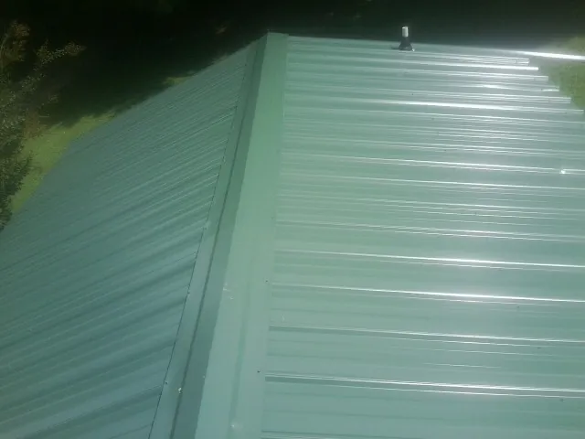 New green metal panels meeting at the ridge of a roof — Flat Roof Repair work by our crew in Parowan
