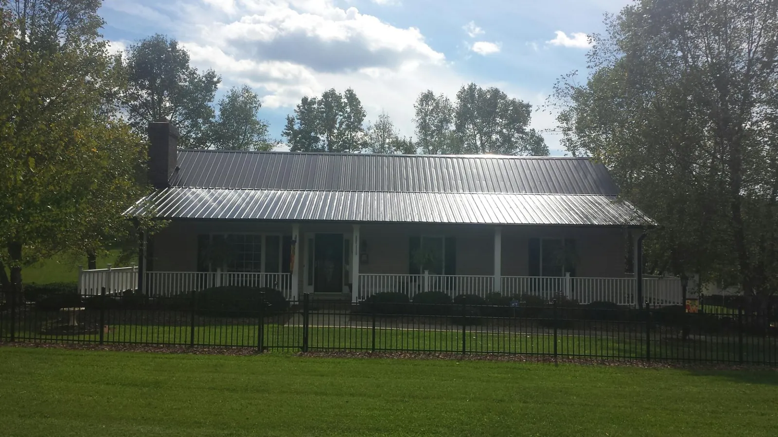Gray metal roof on a brick ranch with a full width front porch — Gutter Guard Installation work by our crew in Parowan
