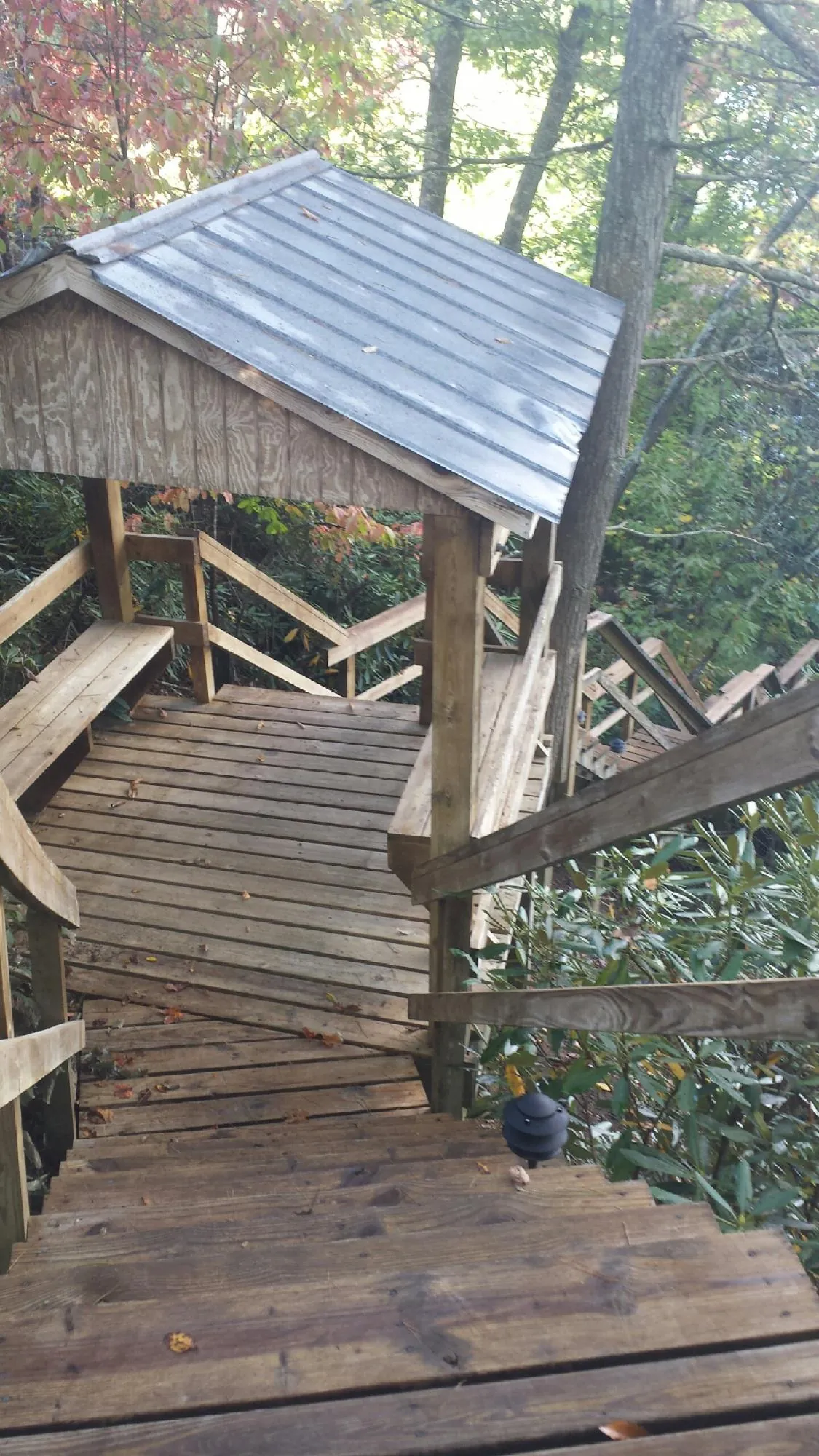 Metal roofed shelter over wooden steps on a wooded walkway — Skylight Repair & Installation work by our crew in Parowan