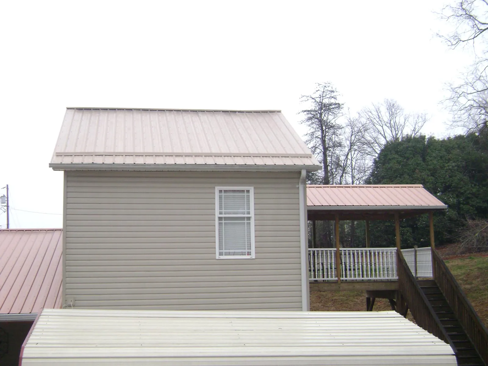 Tan metal roofs on a two story addition and attached porch, from a Roof Replacement job in Parowan